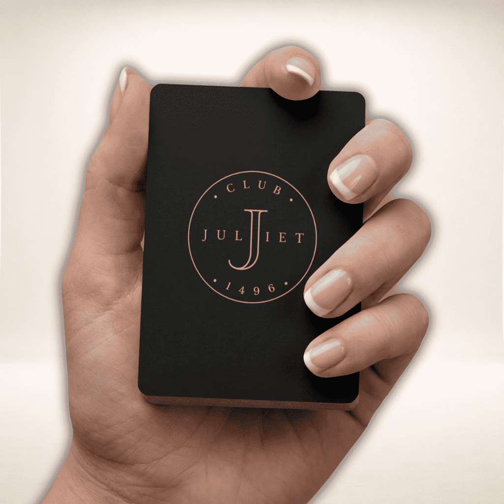 Hand hält das schwarze Club Juliet Pokerkarten-Set mit goldenem Logo