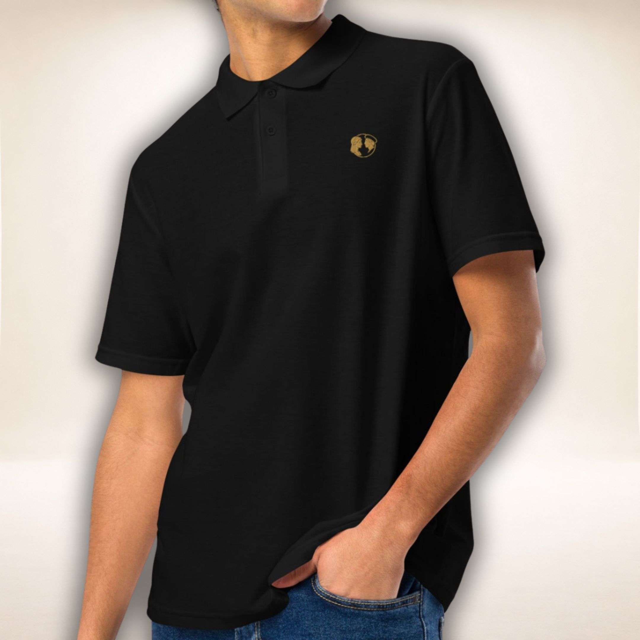 Schwarzes Belgravia Polo mit goldenem Doppelprofil-Logo, von einem Mann getragen