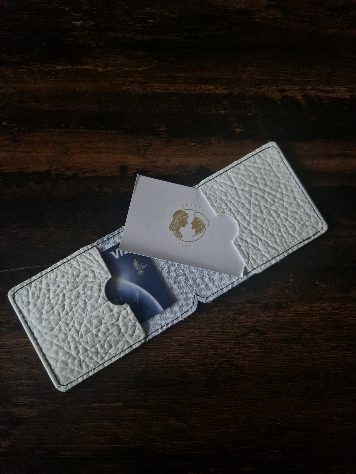 Beige Kartenhülle mit Espresso-Motiv neben Schlüssel und Sonnenbrille auf einer Ablage im Eingangsbereich.
